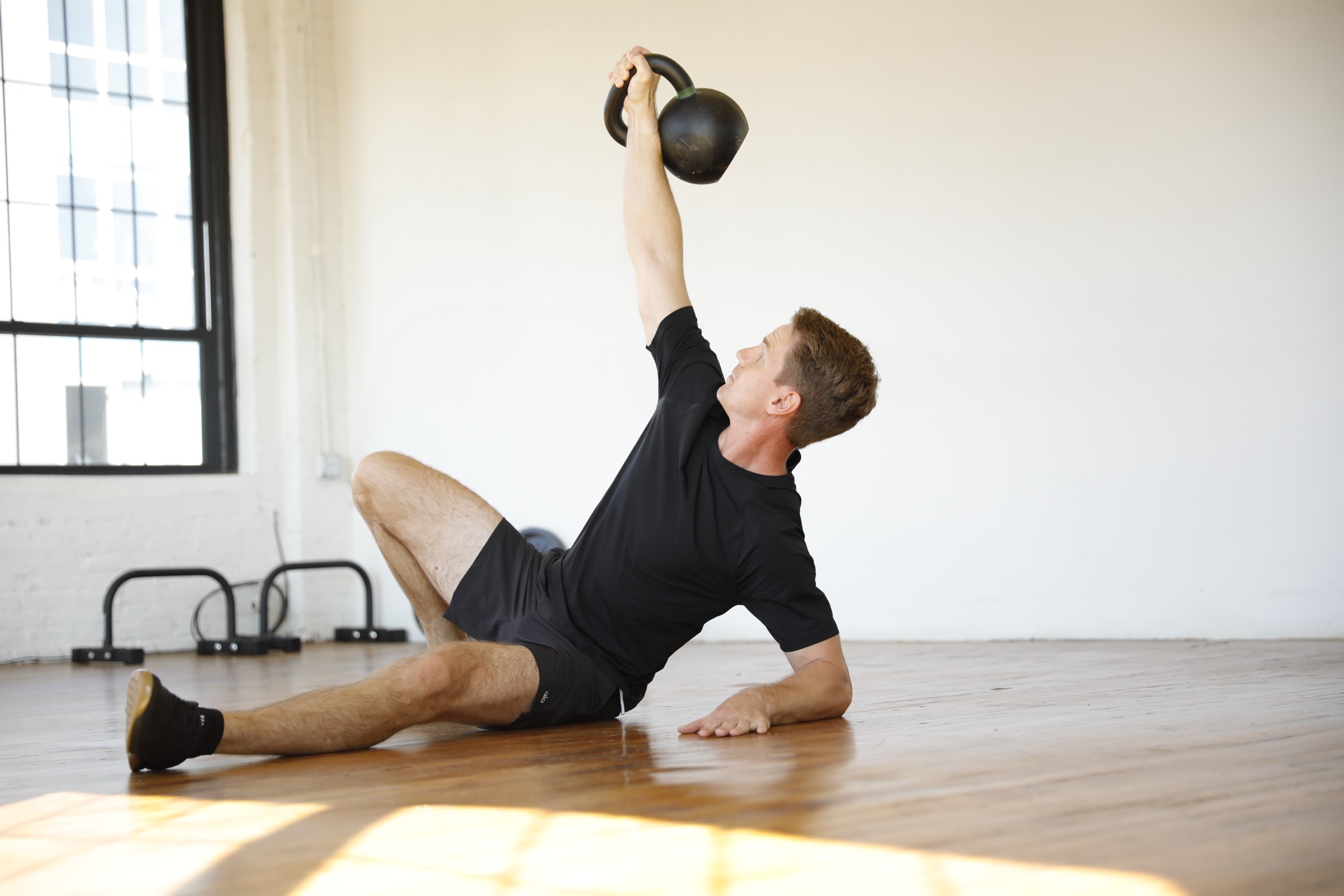 Alexey Myshevskiy halfway through a Turkish get-up, the kettlebell locked out overhead